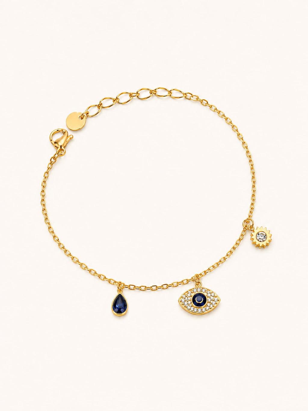 Celestial Evil Eye Charm Bracelet in 18K gold plated stainless steel featuring a sparkling evil eye charm, blue teardrop crystal, and sun charm with CZ accents.