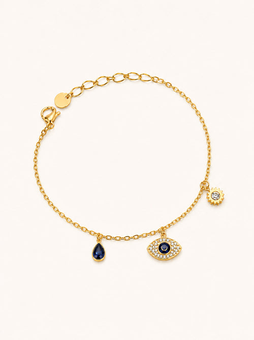 Celestial Evil Eye Charm Bracelet in 18K gold plated stainless steel featuring a sparkling evil eye charm, blue teardrop crystal, and sun charm with CZ accents.