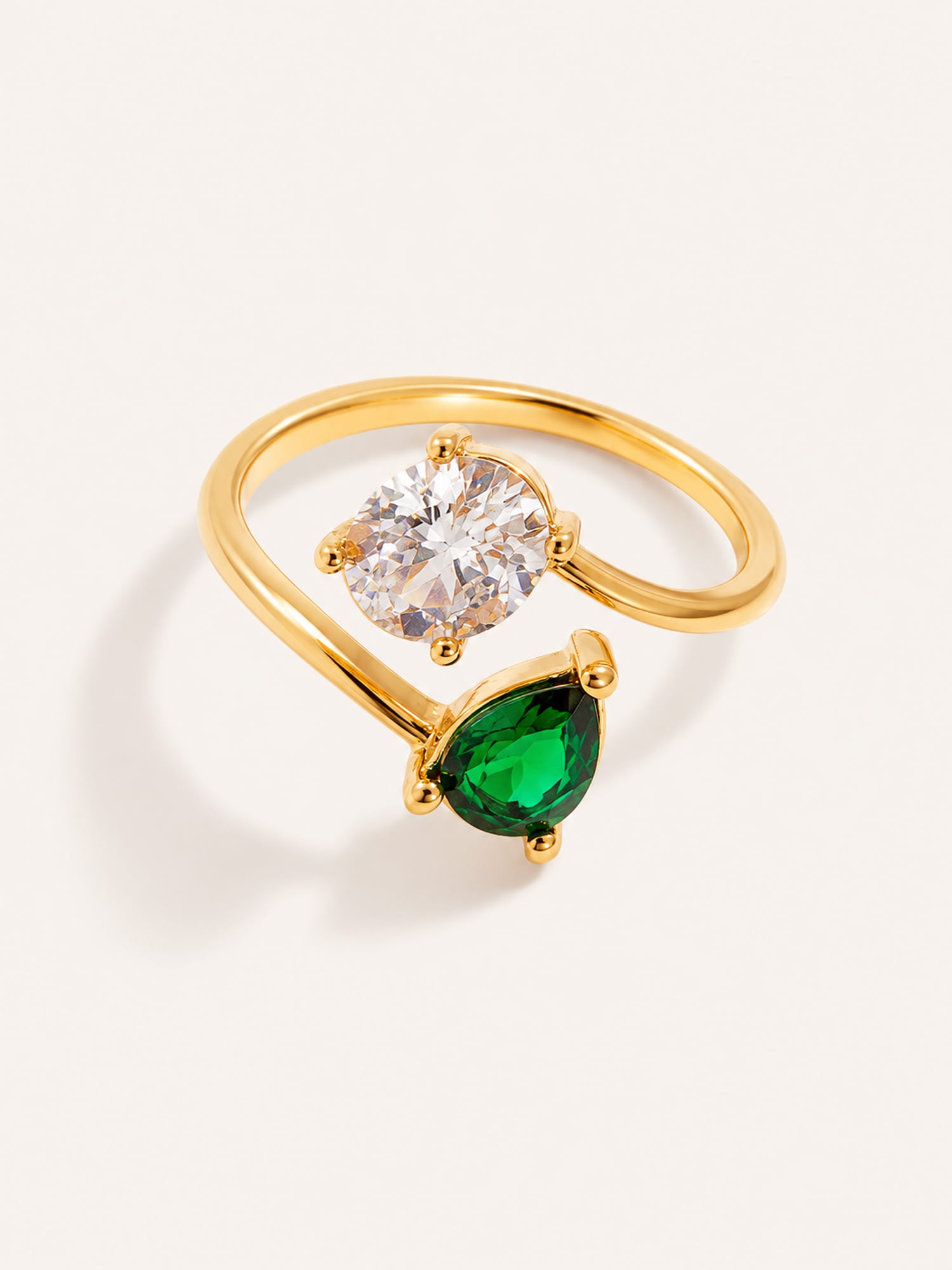 Open ring featuring round white and pear-cut green CZ stones in a polished gold finish.
