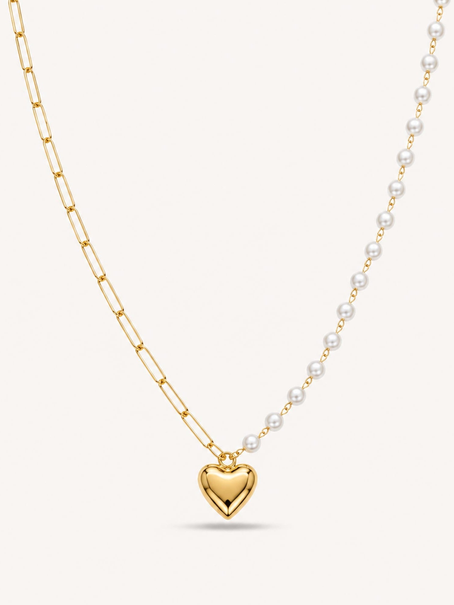 Asymmetrical heart pendant necklace featuring a paperclip chain and faux pearl chain in 18K gold finish.