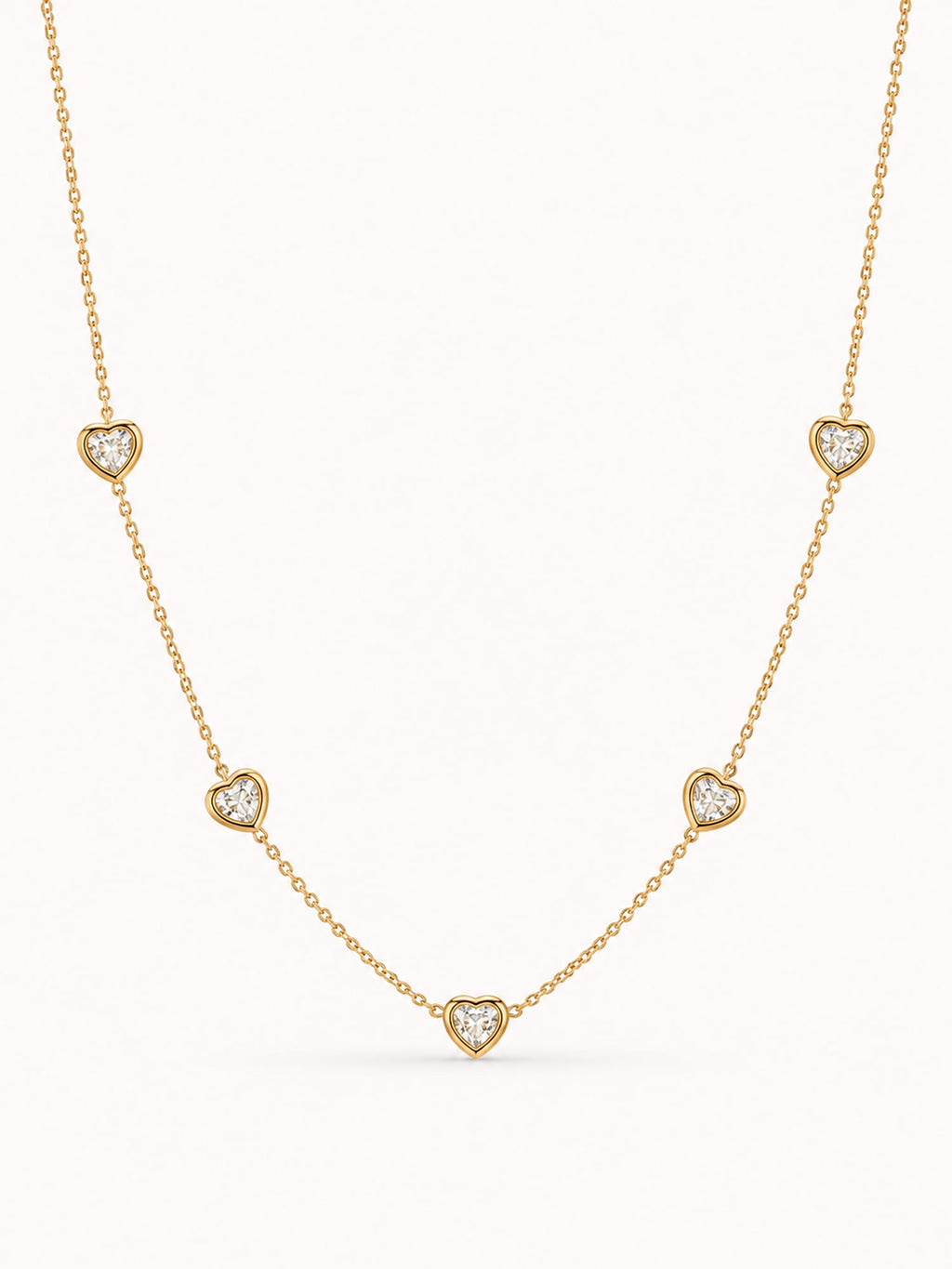 Minimalist heart CZ station necklace with five bezel-set white stones in a polished gold finish.