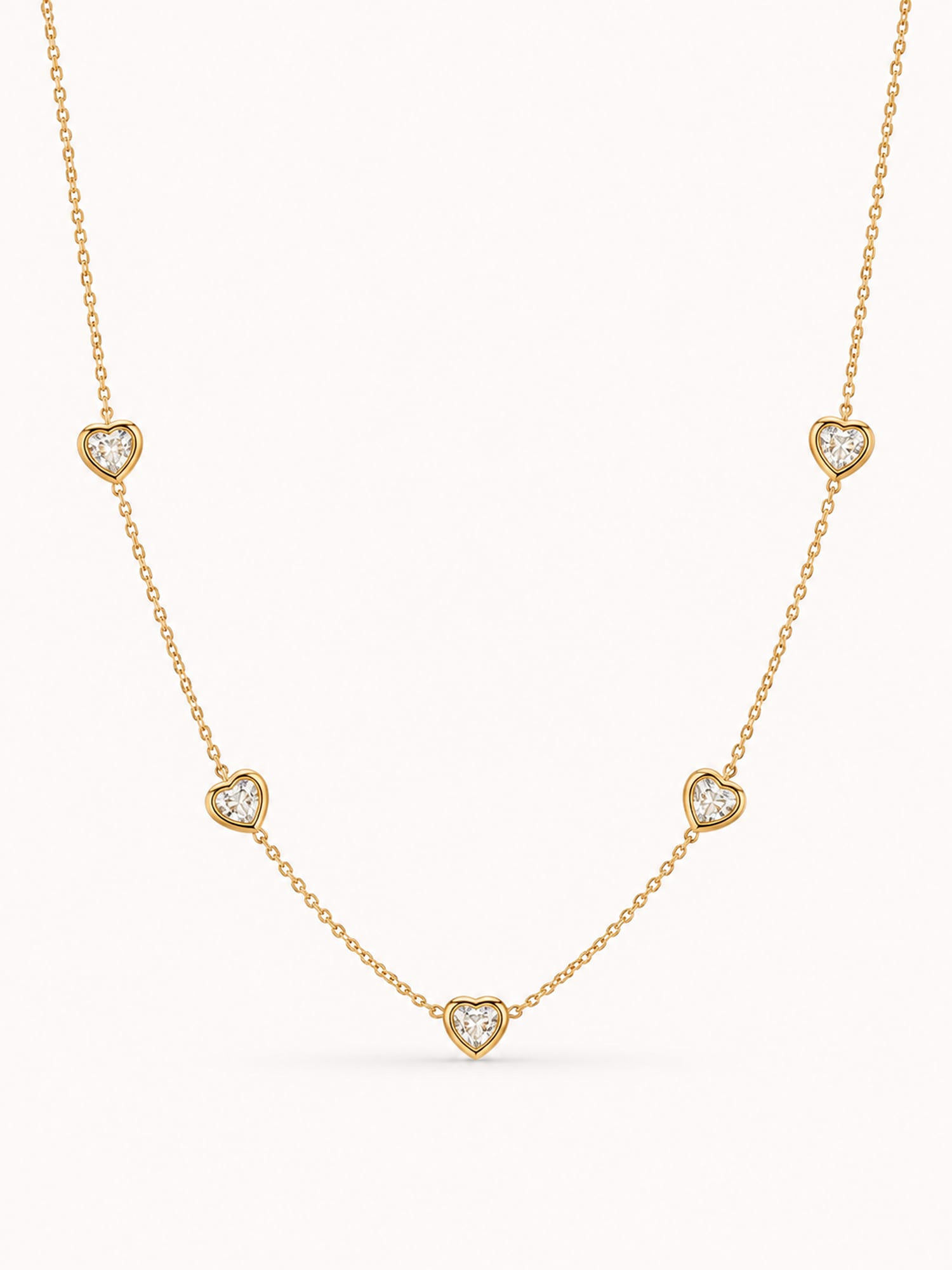 Minimalist heart CZ station necklace with five bezel-set white stones in a polished gold finish.