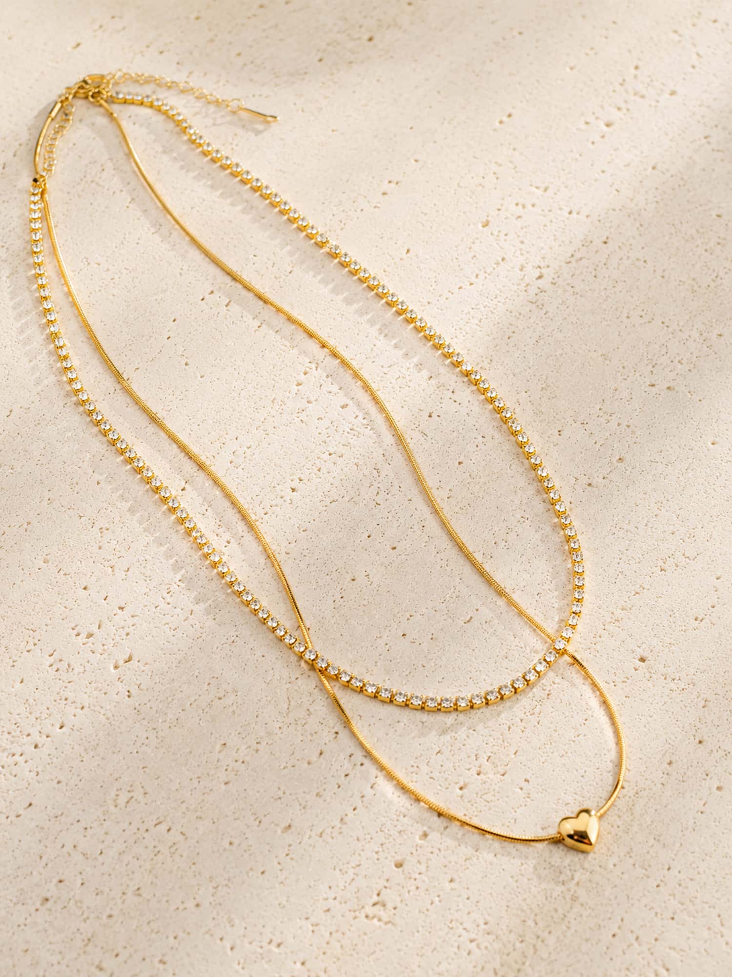Double-layer heart and CZ tennis necklace displayed on a textured stone surface showcasing its elegant layered design.