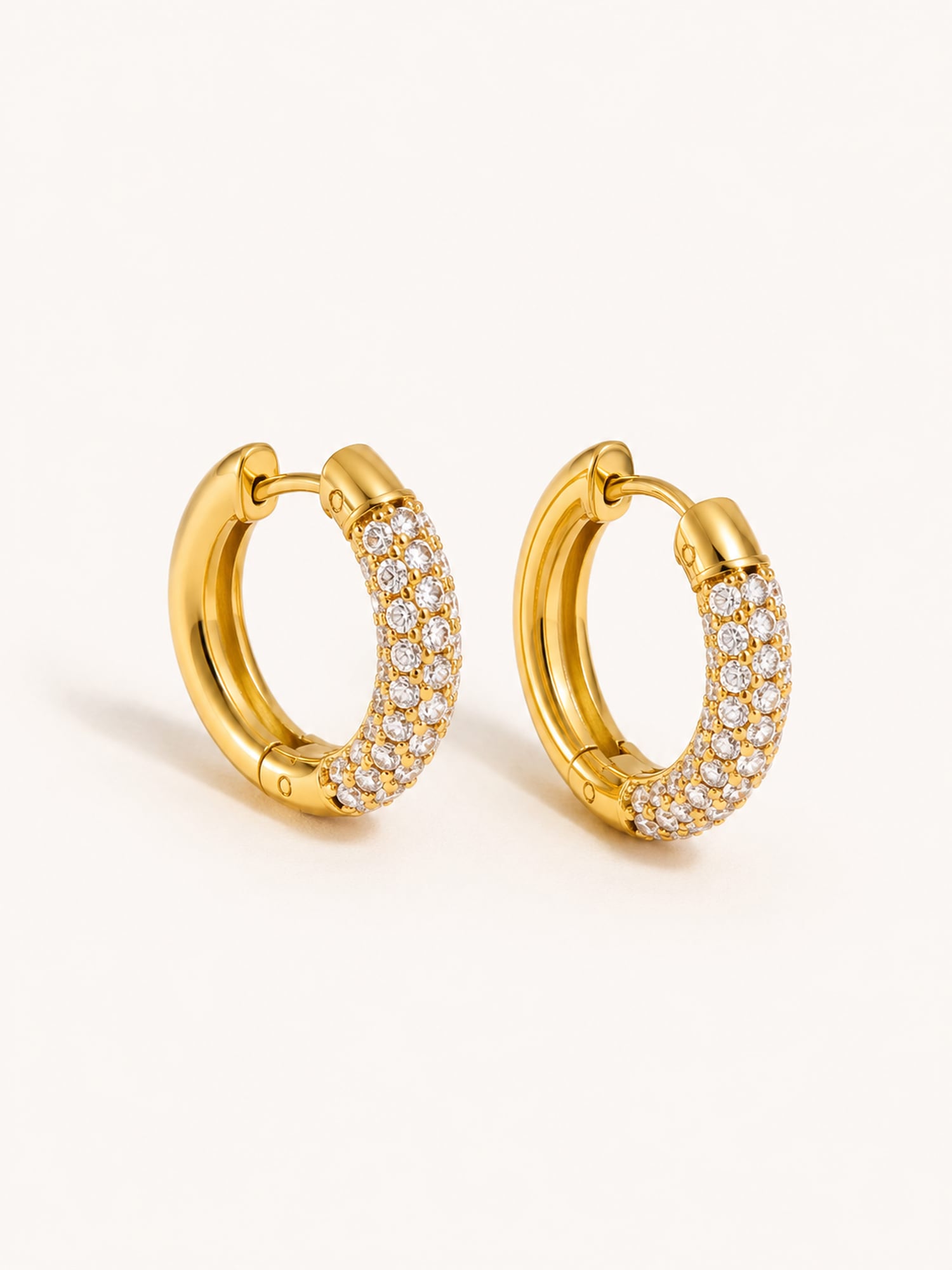 Gold pavé huggie hoop earrings with clear cubic zirconia in a polished stainless steel finish.